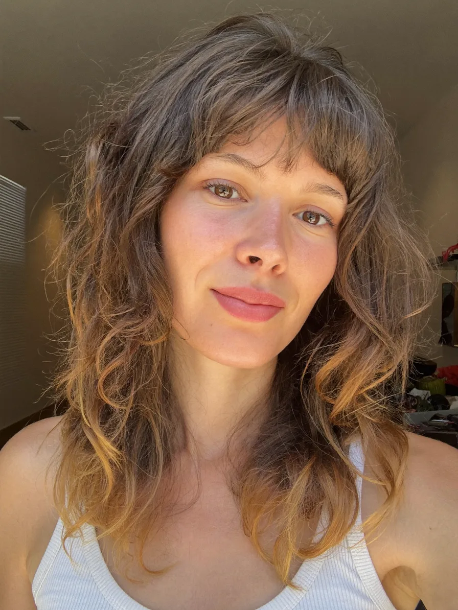 Medium Length Wavy Hair with Feathered Layers and Curtain Bangs