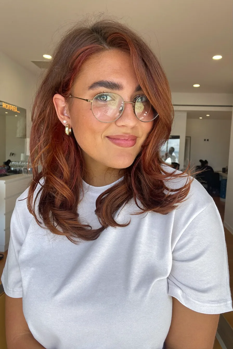 Modern shoulder-length auburn layered waves with side-swept bangs