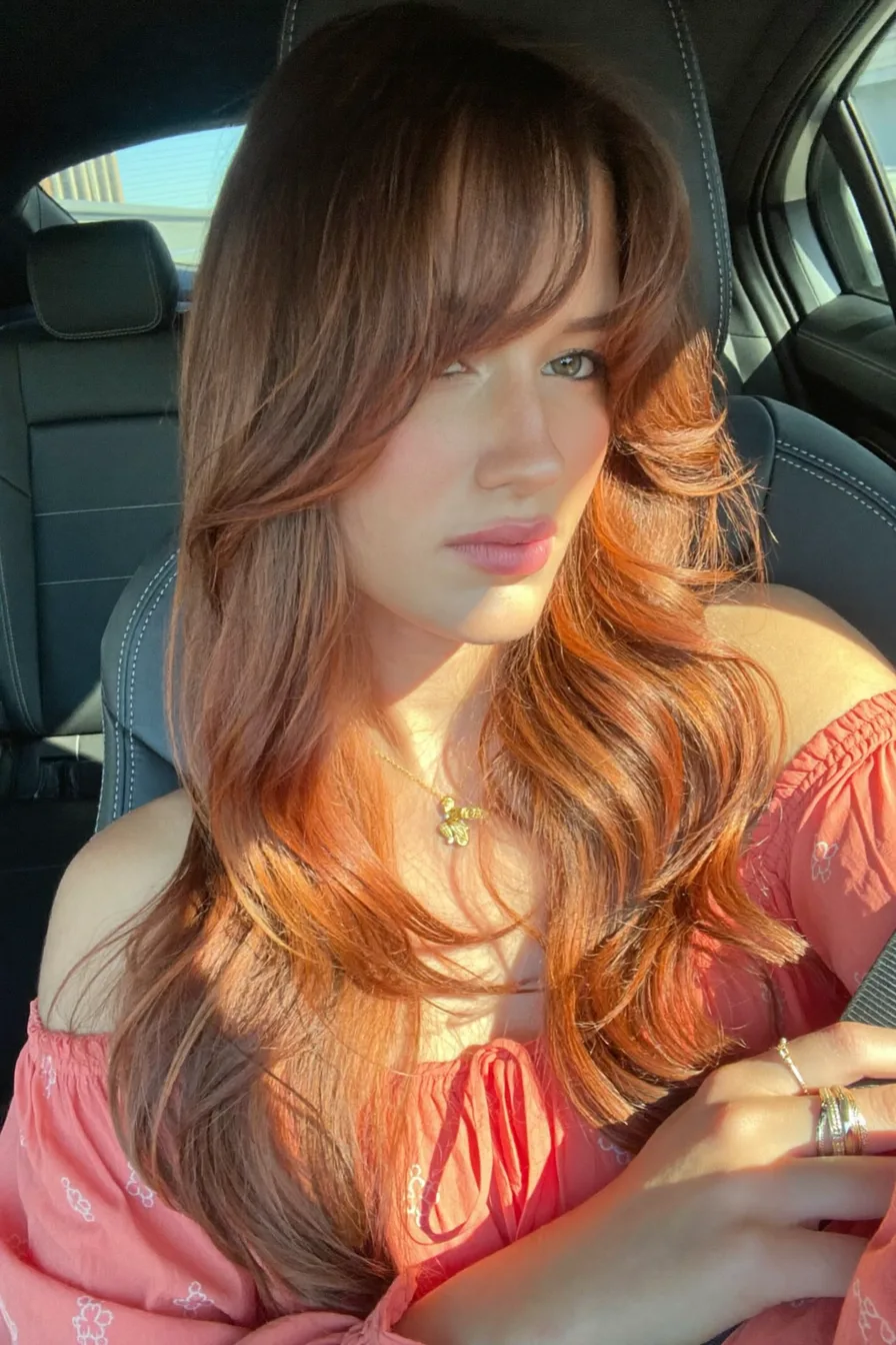 Voluminous Copper Long Layers with Flowing Curtain Bangs