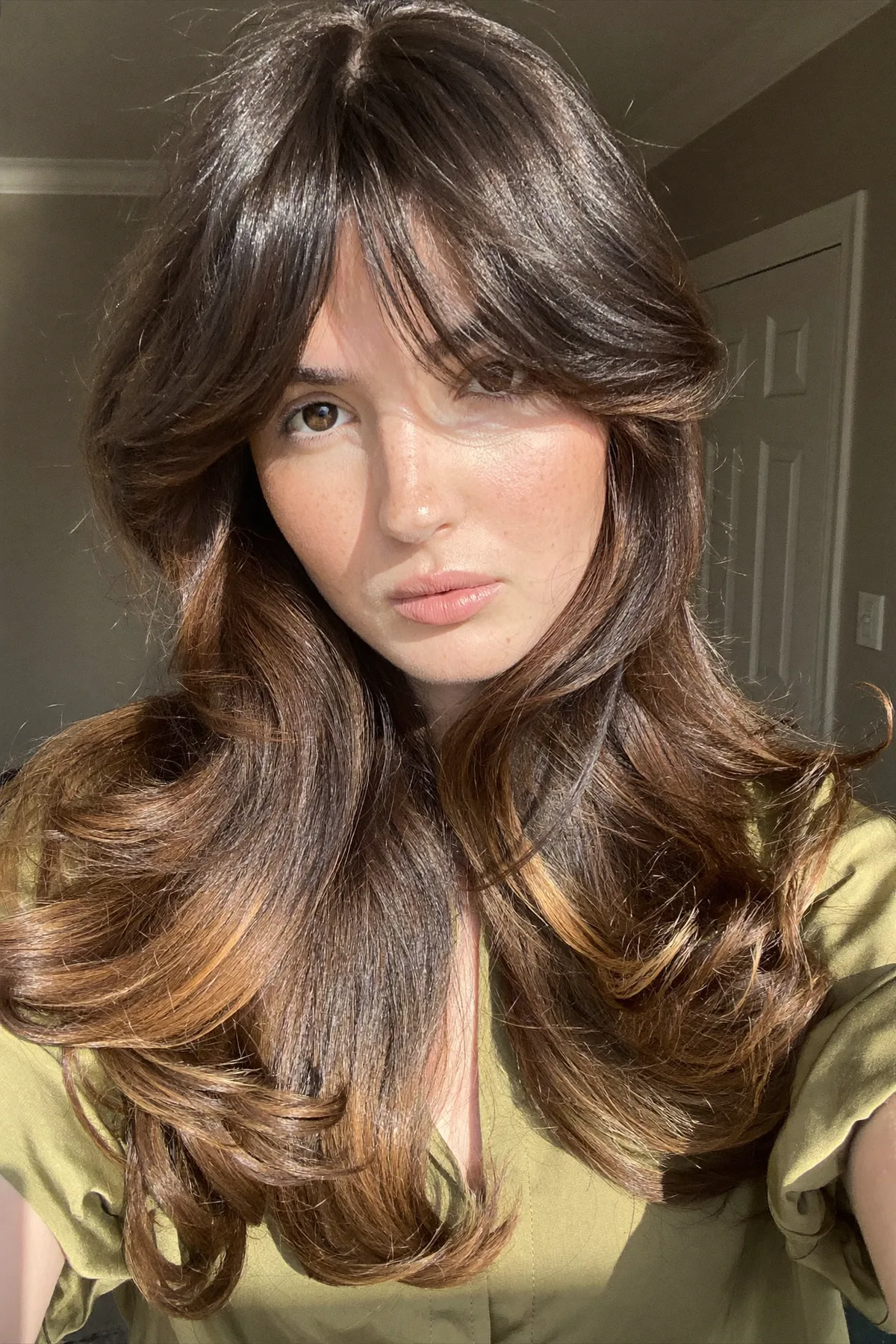 Caramel Bronde Balayage on Long Layered Mid-Back Waves with Curtain Bangs