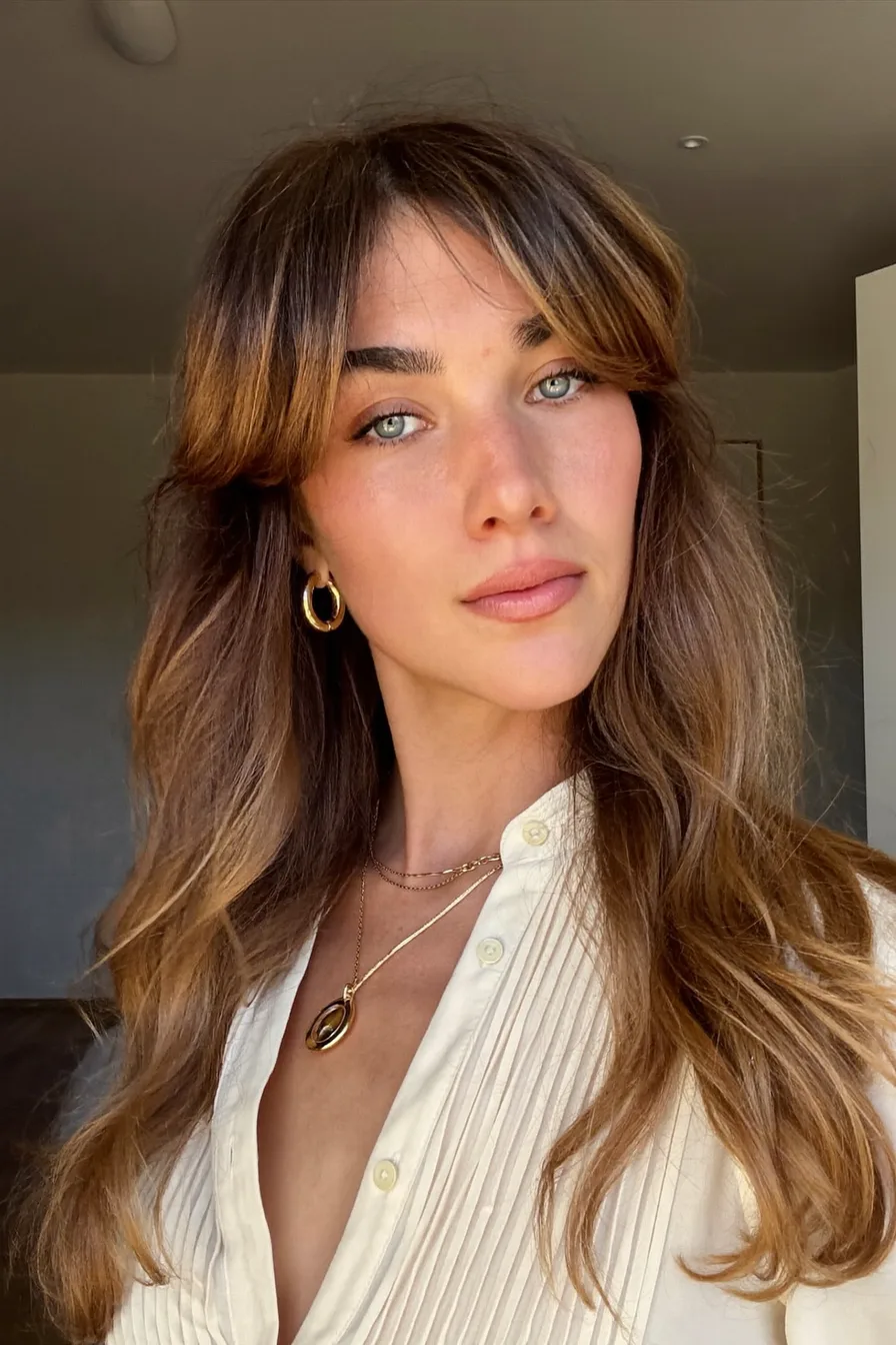 Long Wavy Layers with Warm Caramel Balayage and Curtain Bangs