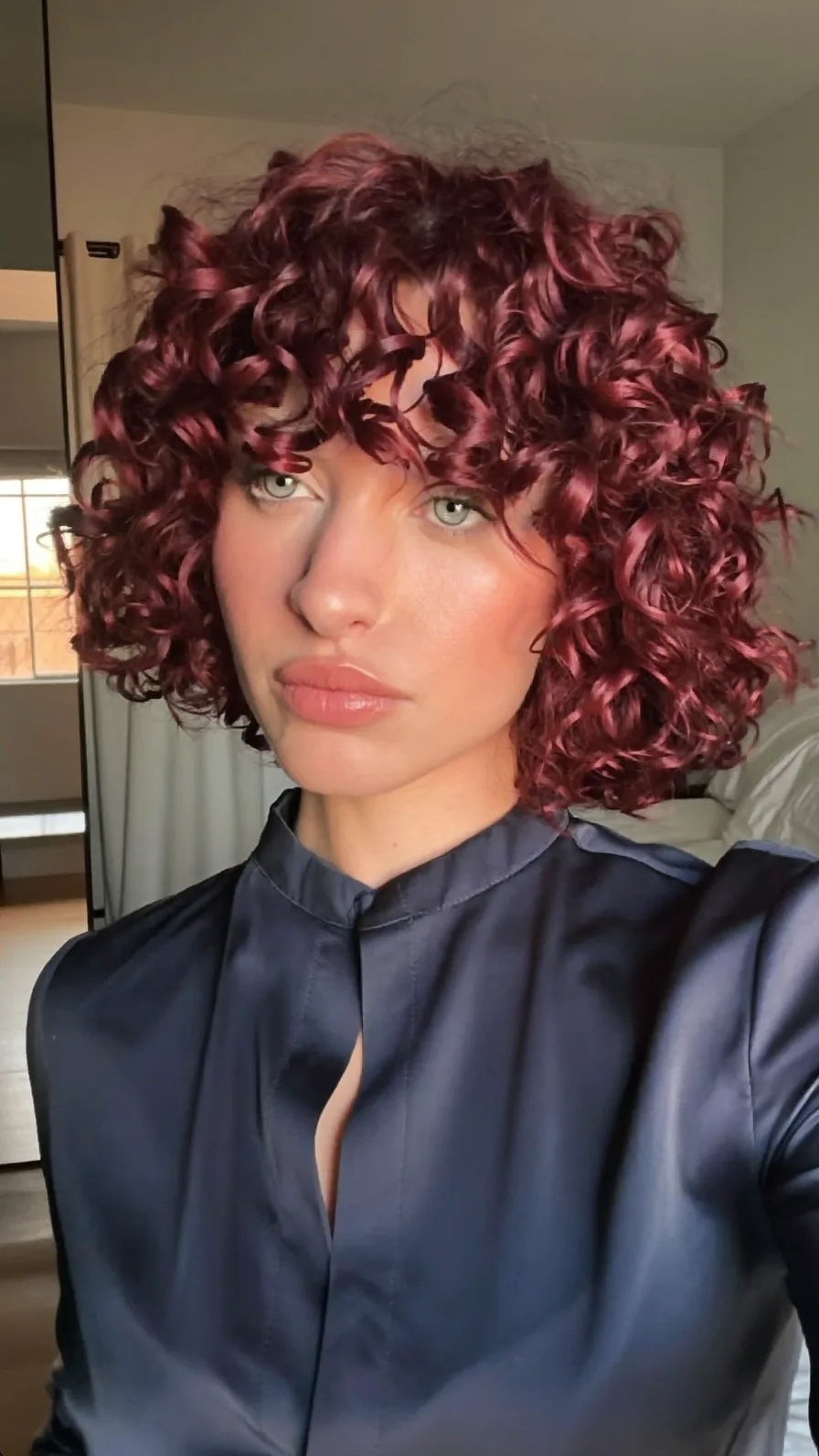 Voluminous Deep Burgundy Curly Chin-Length Bob with Curtain Bangs