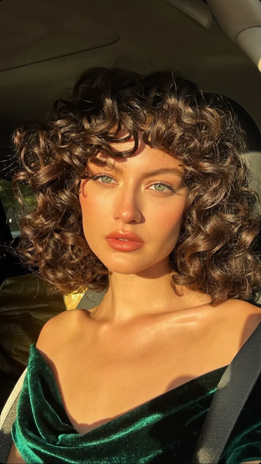 Voluminous Curly Bob with Wispy Bangs and Multi-Dimensional Highlights