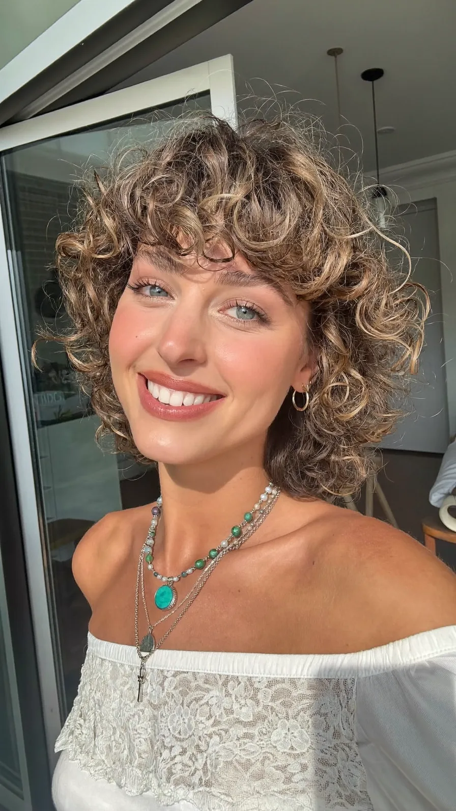 Voluminous Curly Bob with Curtain Bangs and Honey Highlights