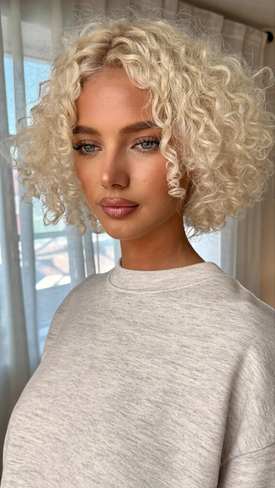 Voluminous Platinum Blonde Curly Bob with Center Curtain Bangs