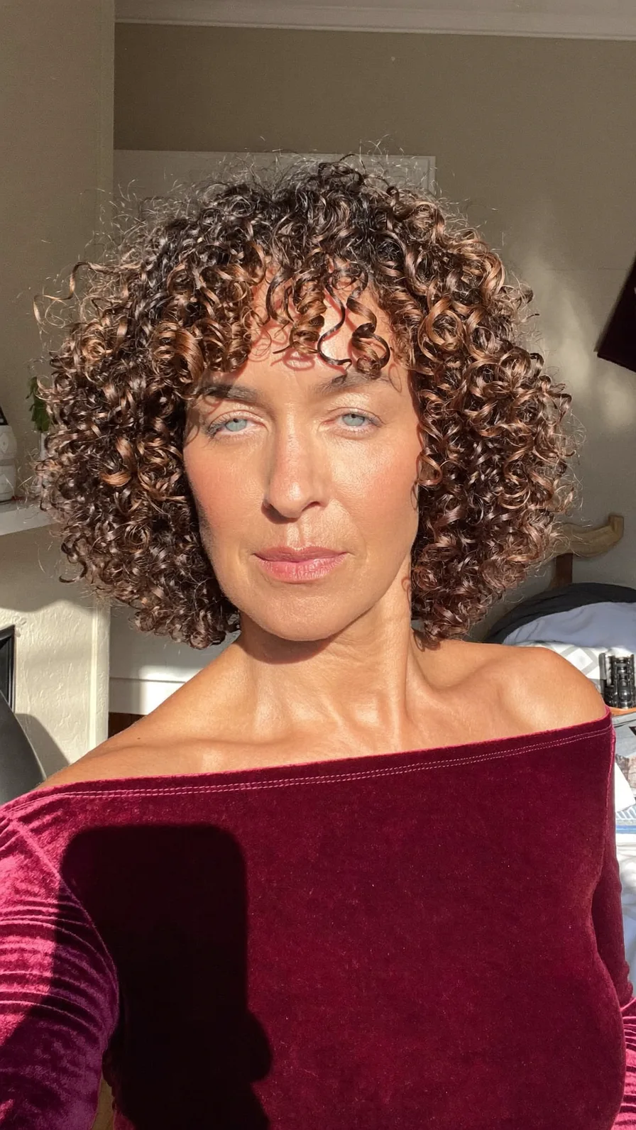 Voluminous Curly Bob with Curtain Bangs and Caramel Highlights