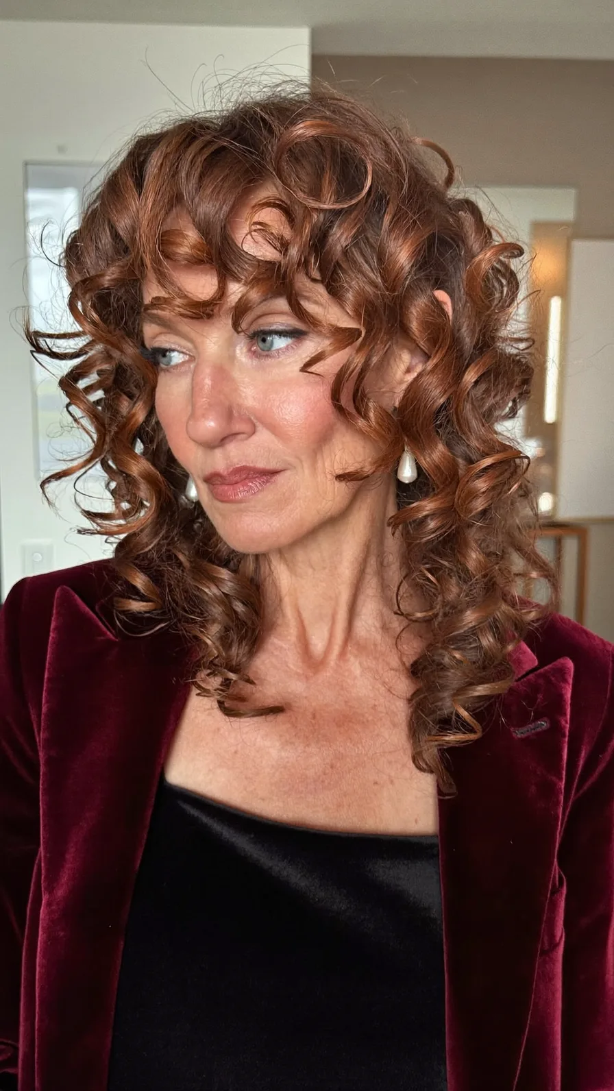 Voluminous Curly Auburn Medium-Length Layers with Curtain Bangs