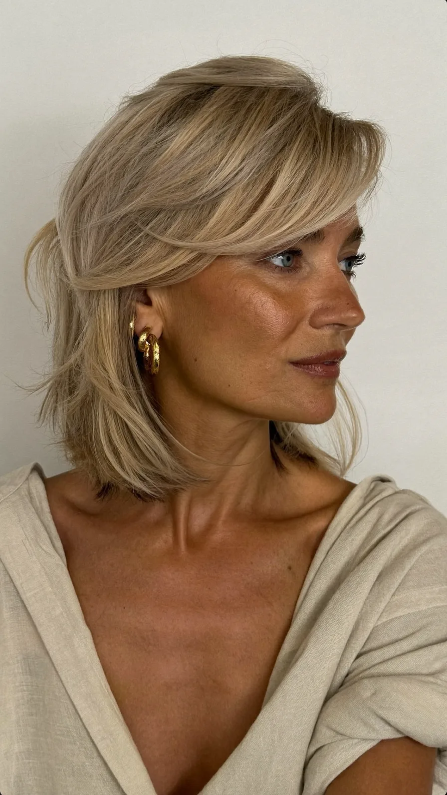 Elegant Shoulder-Length Layered Blonde Hairstyle With Soft Side Bangs