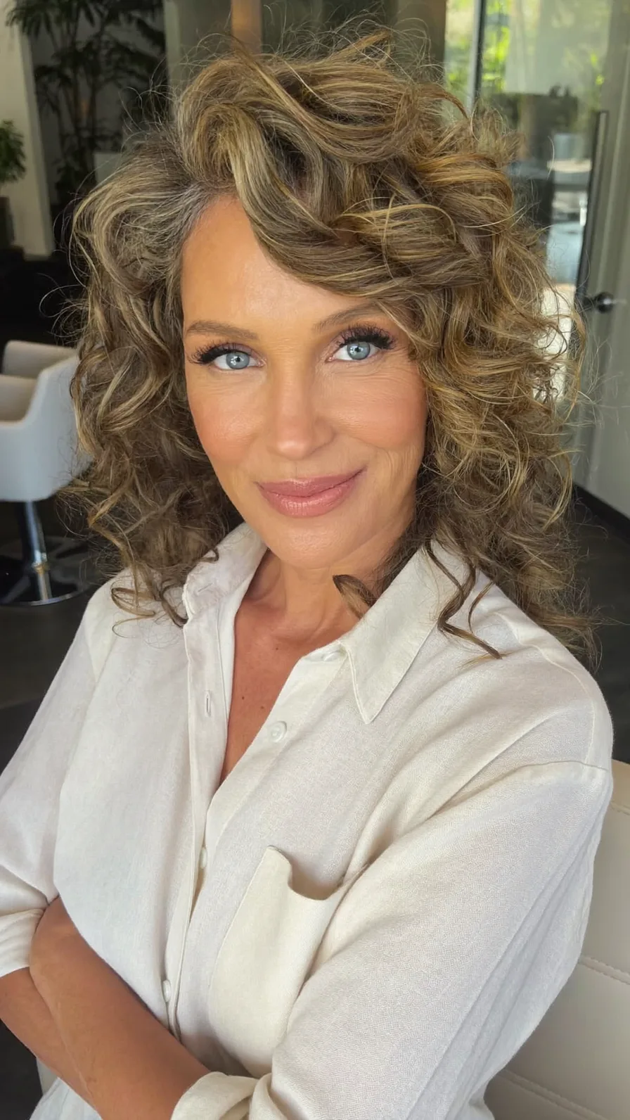 Voluminous Layered Curls with Honey Blonde Highlights and Side Bangs