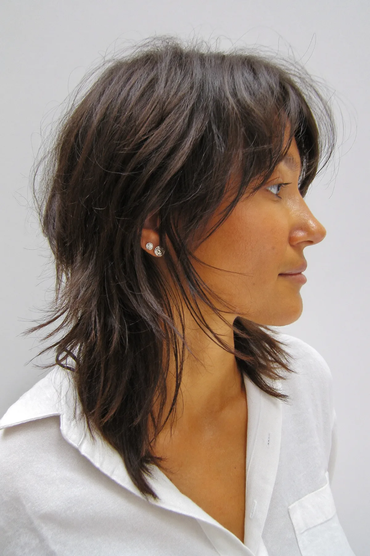 Shoulder-Length Natural Brunette Shag with Wavy Texture and Curtain Bangs