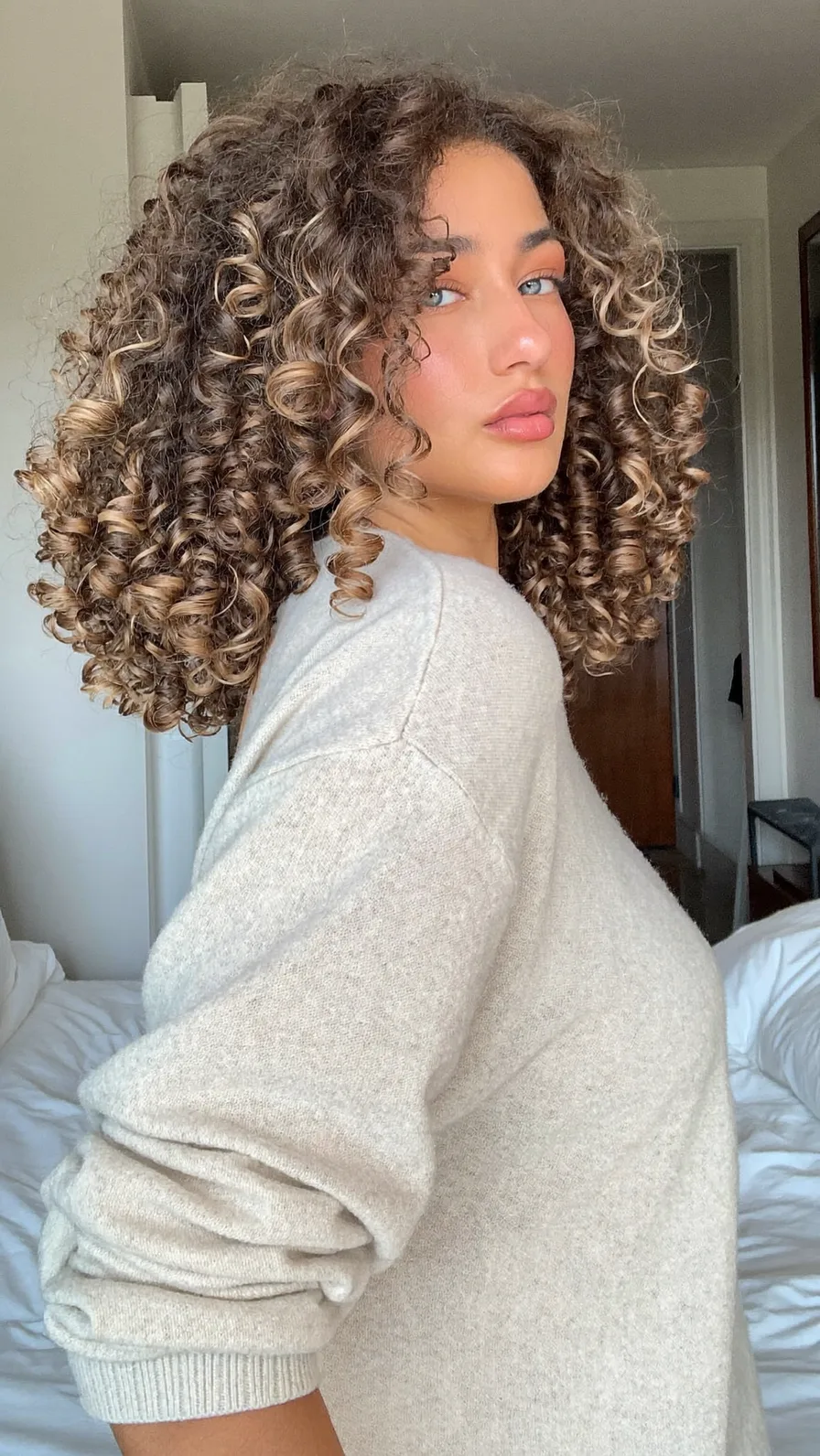 Voluminous Curly Shoulder-Length Hair with Caramel Balayage Highlights