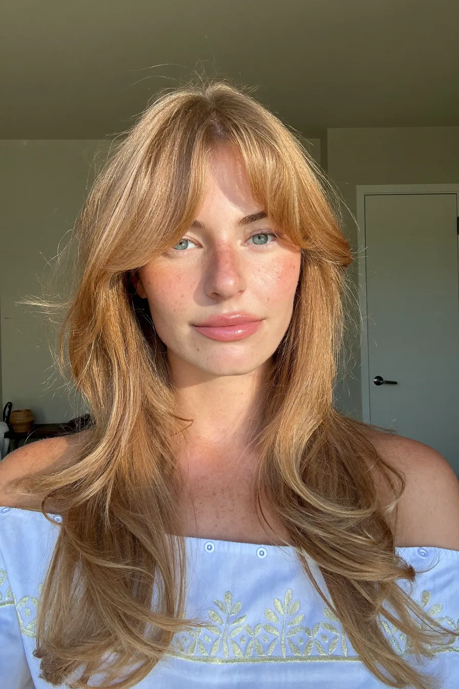 Face-Framing Layers with Curtain Bangs in Strawberry Blonde Hue